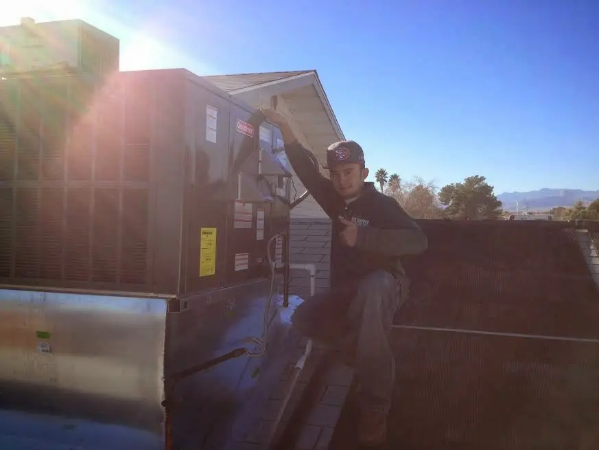 HVAC technician performing AC Tune-Up on a rooftop unit in Sherman